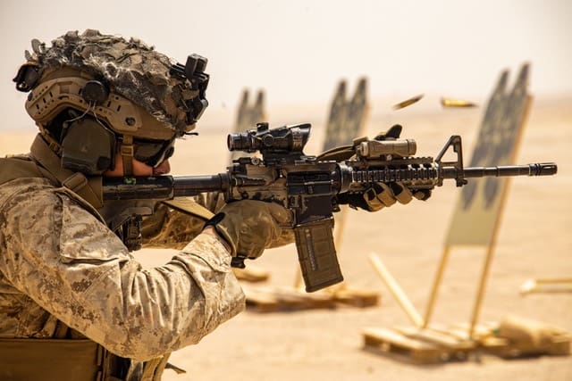 A soldier is aiming his rifle at an obstacle course.