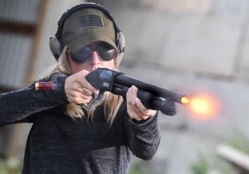 A woman is holding a gun and aiming it.